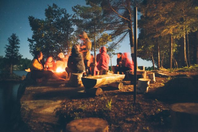 group of military service members near bonfire near trees during nighttime