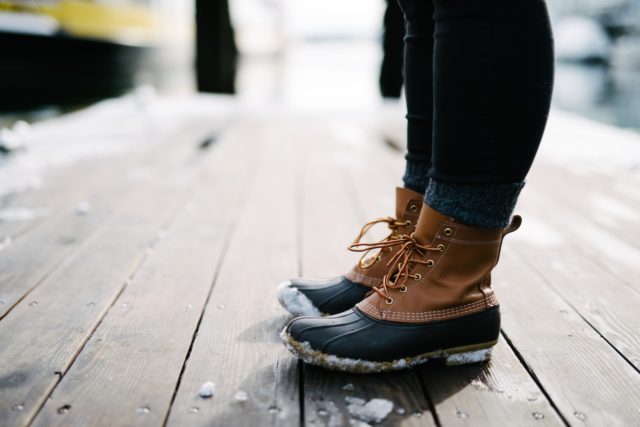 military person wearing brown-and-black leather duck boots standing on brown wooden dock