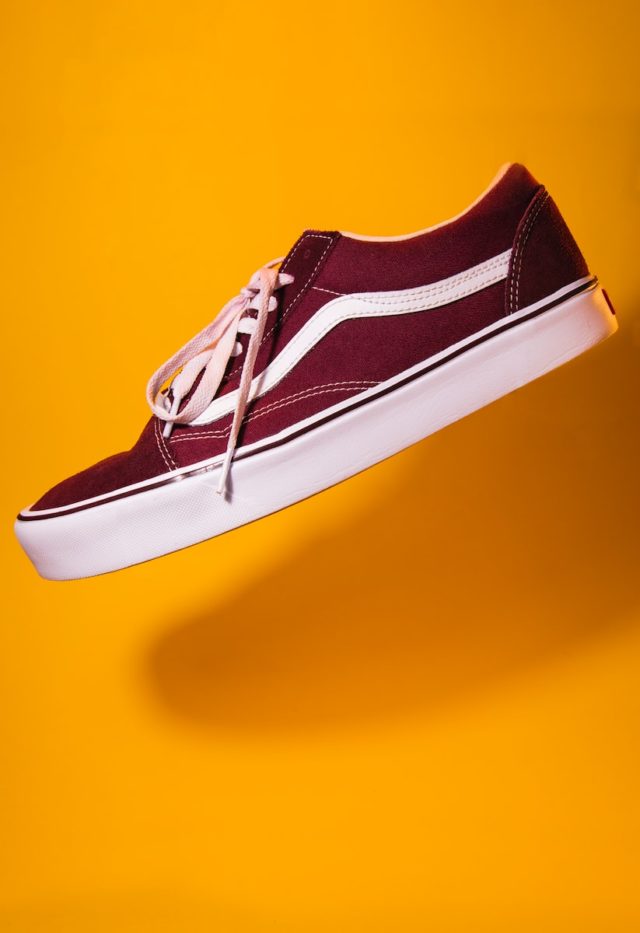 unpaired maroon vans on top of yellow textile