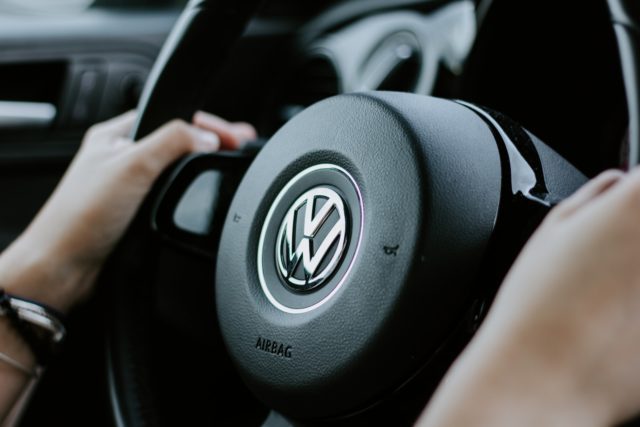 military person holding black Volkswagen steering wheel