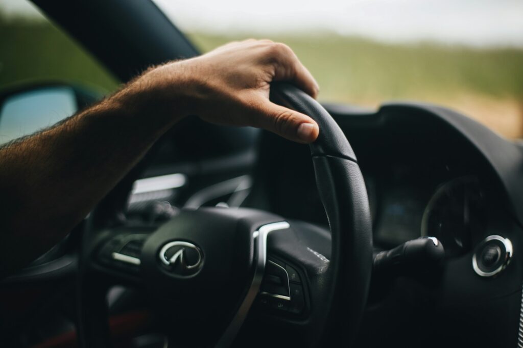 military serviceperson holding black infiniti steering wheel