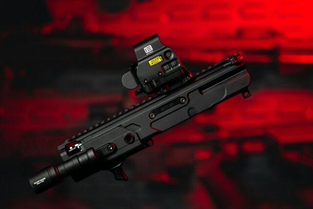 a close up of a rifle with eotech on a red background