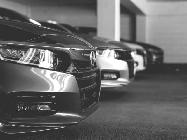 grayscale photo of cars on road for rental